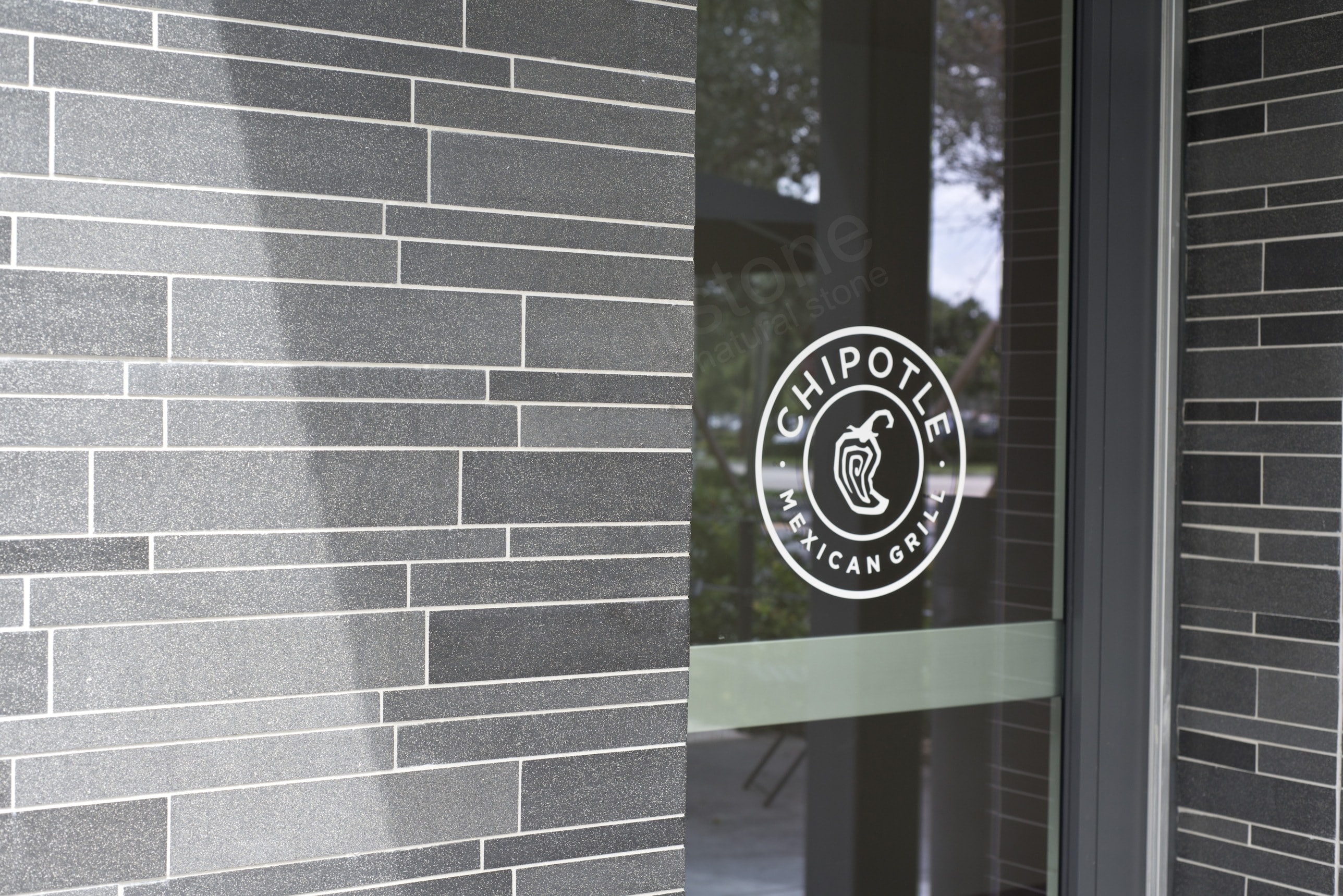 Norstone Lynia Interlocking Tiles in Grey Basalt surrounding the entrance to a Chipotle in South Florida